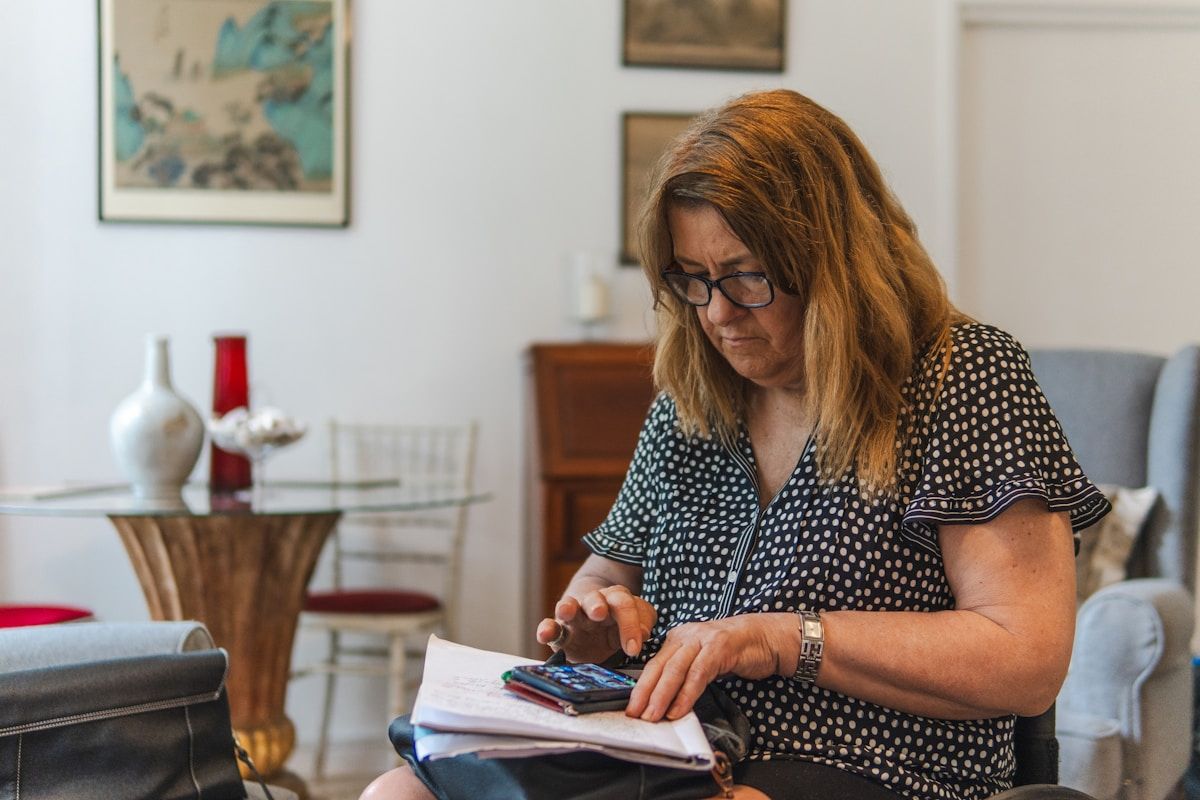 A woman reviewing paperwork and her phone at home